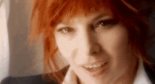 a close up of a woman with red hair smiling .