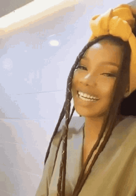 a woman with braids is wearing a yellow turban on her head .