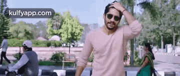 a man wearing sunglasses is standing in a park .