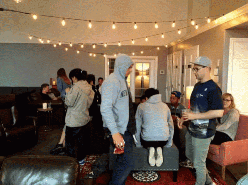 a group of people are gathered in a living room with one man wearing a hoodie that says ny