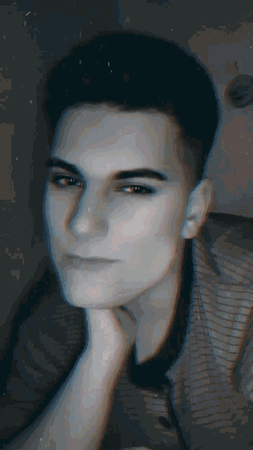 a black and white photo of a young man 's face with his hand on his chin