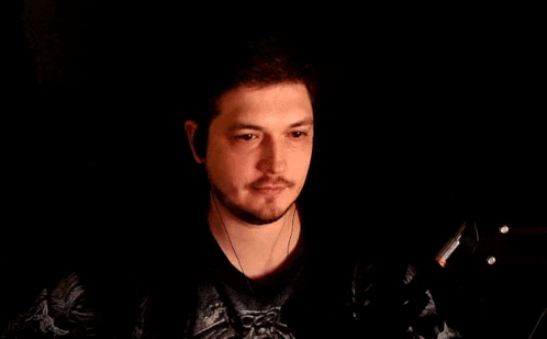 a man is wearing headphones and playing a guitar in the dark .