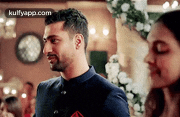 a man and a woman are standing next to each other in a room and looking at each other .
