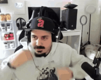 a man wearing headphones and a baseball cap is sitting in front of a microphone .