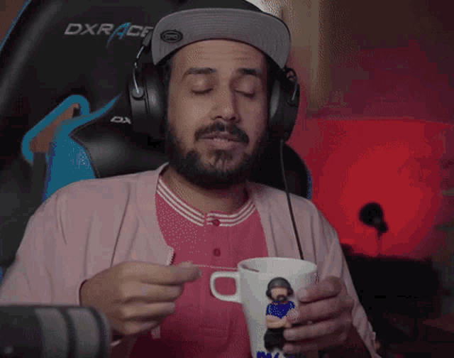 a man wearing headphones is holding a cup of tea