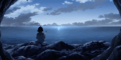 a person sitting on a rock looking out over the ocean