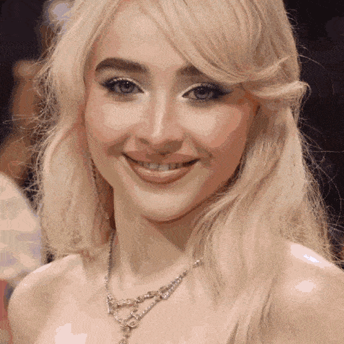 a close up of a woman 's face with a necklace on