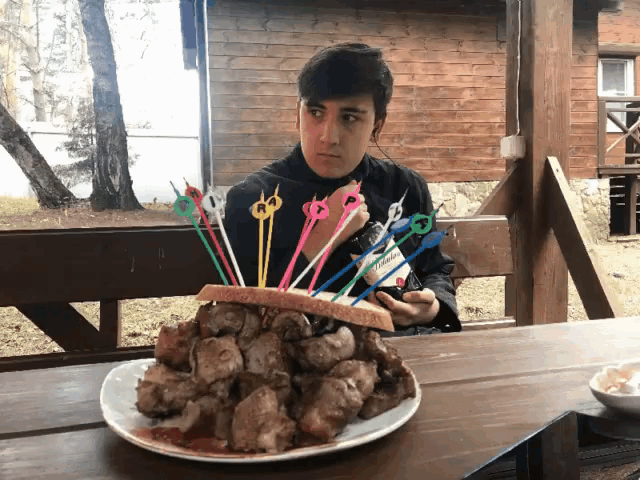 a man is sitting at a table with a plate of food and a bunch of toothpicks
