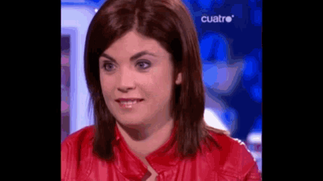 a woman in a red jacket is smiling in front of a blue background with the word cuatro on it