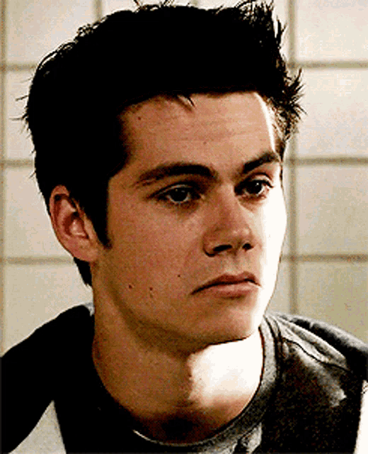 a close up of a young man 's face with a tiled wall in the background