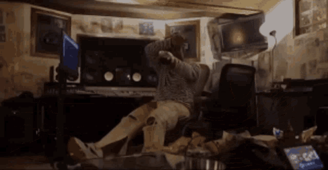 a man is sitting in a chair in a messy room with his feet on the floor
