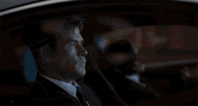 a man in a suit and tie is sitting in a car
