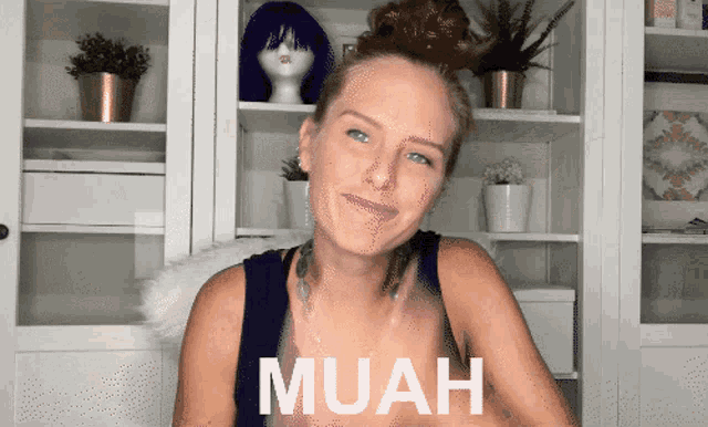 a woman wearing a black tank top with the word muah written on it
