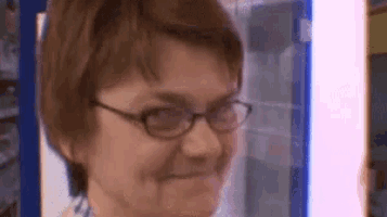 a woman wearing glasses is smiling and looking at the camera in a blurry photo .