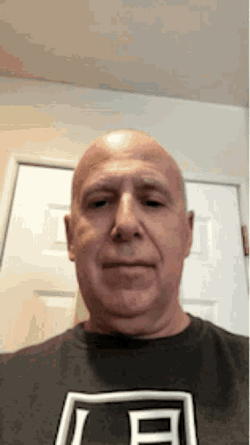 a bald man is wearing a black shirt with the letter e on it .