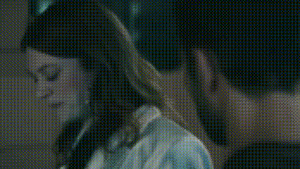 a man and a woman are looking into each other 's eyes in a dark room .