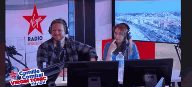 a man and a woman are sitting in front of a virgin radio sign