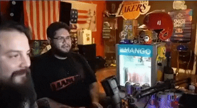 two men are sitting in front of a refrigerator that says mango on it