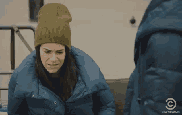 a woman wearing a beanie and a blue jacket is standing next to a man in a blue jacket .