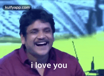 a man is laughing and saying `` i love you '' while wearing a red shirt .