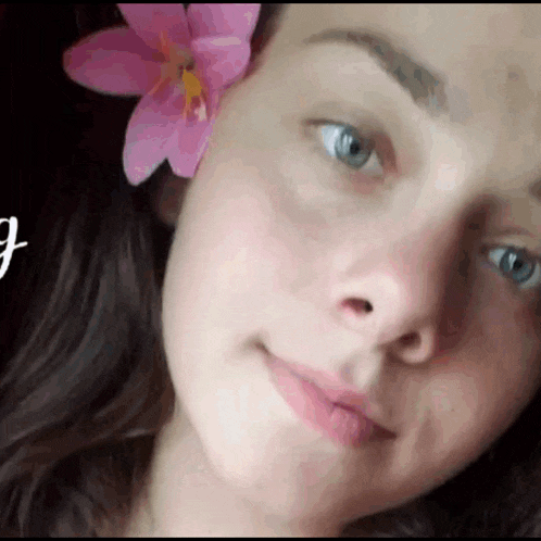 a close up of a woman with a pink flower in her hair