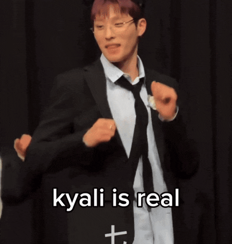 a man in a suit and tie is dancing with the words " kyani is real " behind him