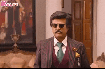 a man in a suit and tie wearing sunglasses is standing in front of a painting .