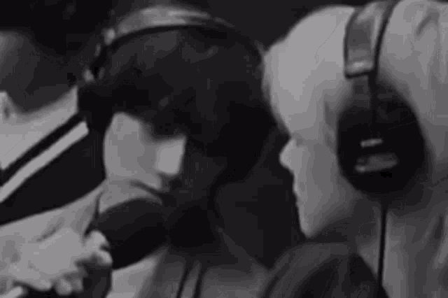 a man and a woman wearing headphones are sitting next to each other in front of a microphone .