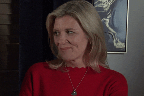 a woman wearing a red sweater and a silver necklace is smiling