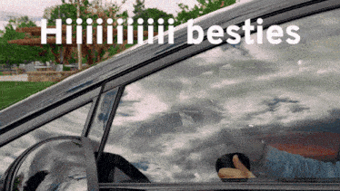 a man is driving a car with the words " hiiiiiiir besties " on the window