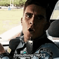 a police officer is sitting in the driver 's seat of a police car and saying i 'm mouthing no .