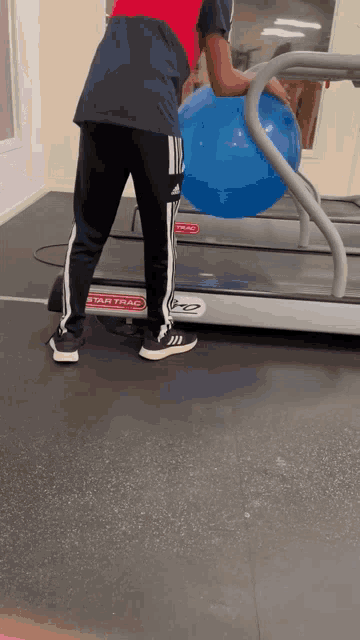 a man is holding a blue ball on a treadmill that says star trac