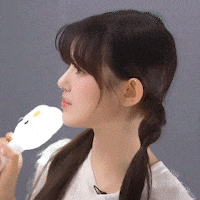 a woman with pigtails is holding a white object to her face