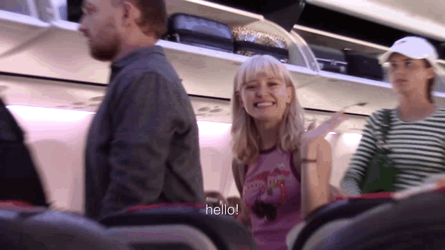 a woman on an airplane says hello to another woman