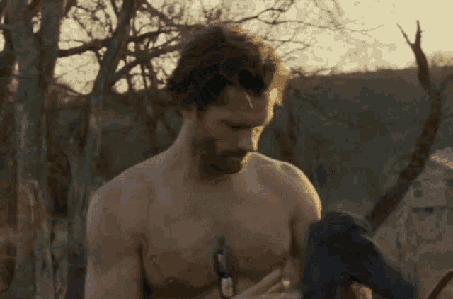 a shirtless man with a beard is holding a camera