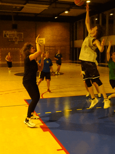a group of people are playing basketball in a gym with a sign on the wall that says ' a '