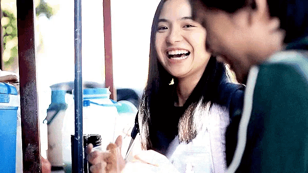 a man and a woman are laughing together and the woman is holding a drink