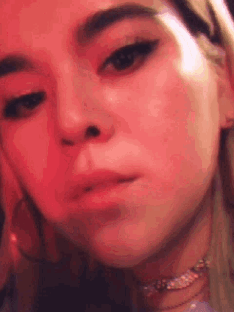 a close up of a woman 's face with a red background and a choker .
