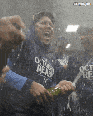 a man wearing a shirt that says october ready is holding a bottle of champagne