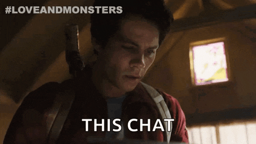 a man in a red shirt is sitting in front of a window and says this chat