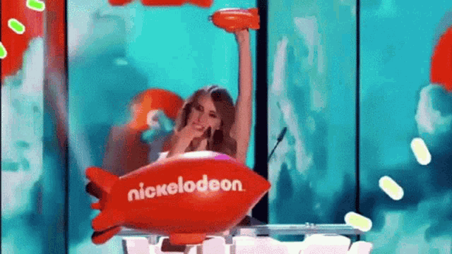 a woman in a nickelodeon airplane holds up a trophy