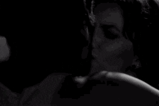 a man and a woman are kissing in a dark room .