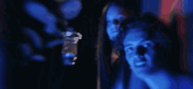 a man and a woman are standing in a dark room with blue lights on their faces .