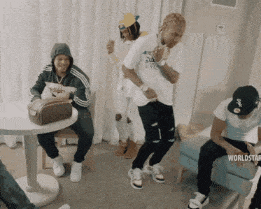 a group of young men are dancing in a room with a white sox hat on