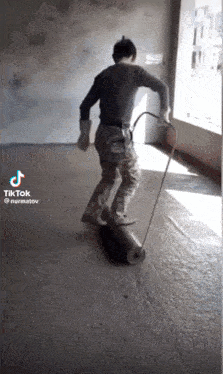 a man is rolling a roll of concrete on the floor while wearing gloves .