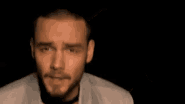 a man with a beard is reaching out his hand towards the camera in a dark room .