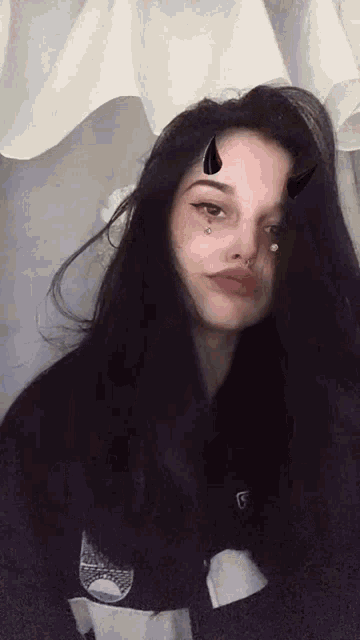 a woman with long black hair and horns on her face