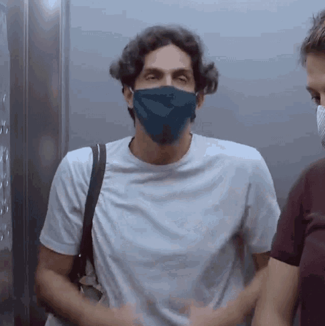 a man wearing a blue face mask is standing in an elevator