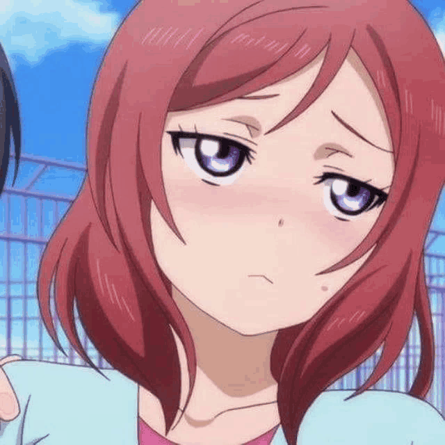 a close up of a anime girl with red hair and purple eyes making a funny face .