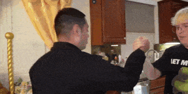 a man wearing a shirt that says " let me " holds another man 's arm